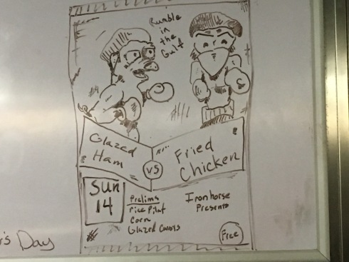 Picture of a boxing match poster with two chickens dressed like boxers on it. Above them it says, "Iron Horse Presents: Rumble in the Gulf." Below them it says, "Sunday 14: Glazed Ham vs Fried Chicken